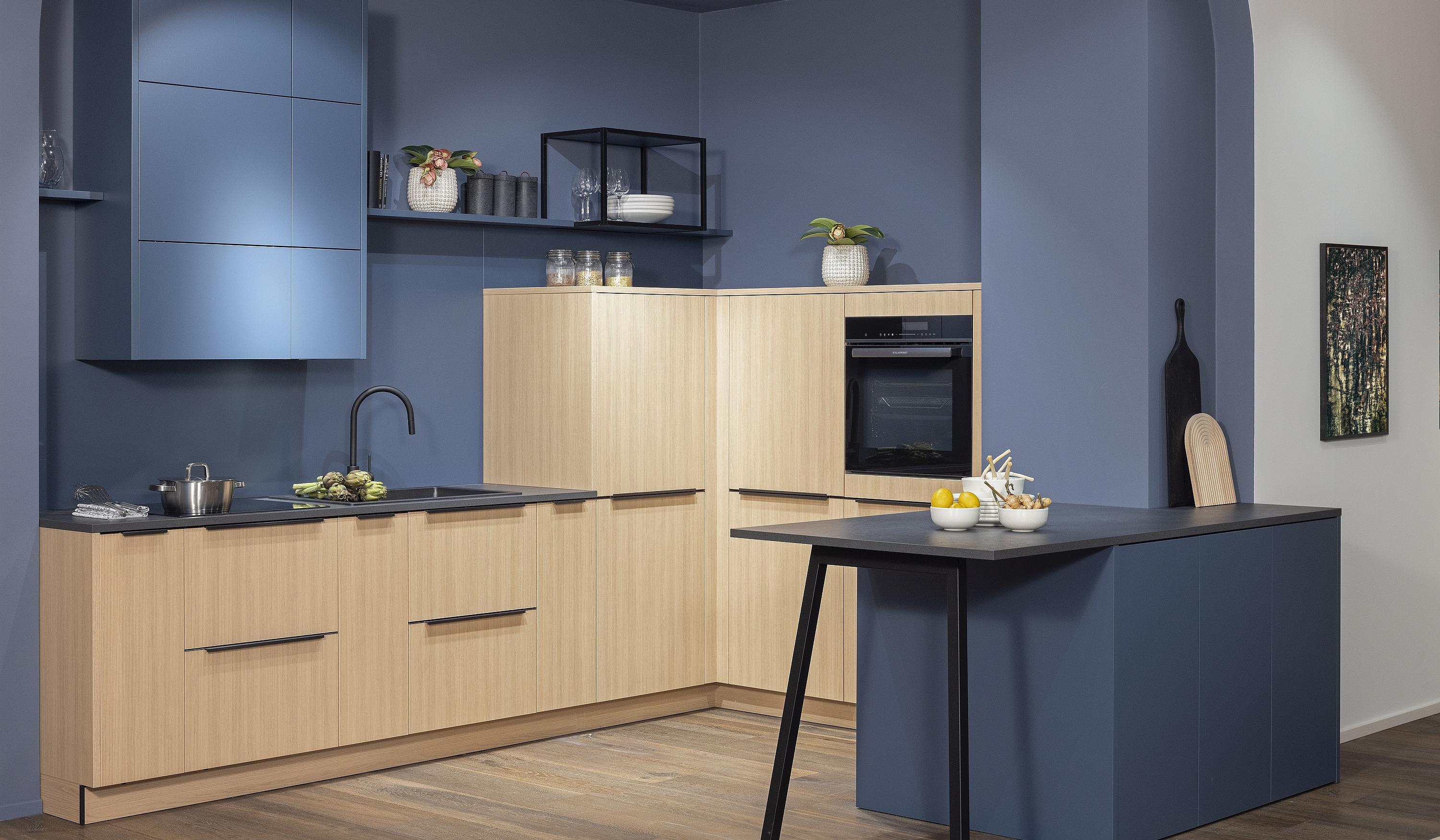 Häcker Küche in einer Nische mit freistehender Theke Küchenschränke in Baltic Blau und in linear gemusterter Eiche Wandanstrich im selben Blau